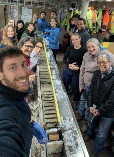 Kasten Core sampling with the science team at shift change over Left side from front to back: Luca Zurli; Laura De Santis; Fiorenza Torricelli; Sarah Jessop; Rebecca Knight; Ana Gomes; Sally Lau; Amy Wells and Timothy Nugroho; Right side from front to back: Amy Leventer, Joline Lalime; Jan Strugnel; Jan Jansen; Noah Menner; Talia Hawkes; Gina Paroz; and Tritan Cordier. Image credit: Luca Zurli.