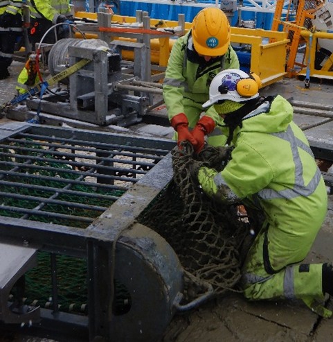 Scientists looking through the net of the sled for organisms. Image credit: J. Lalime.